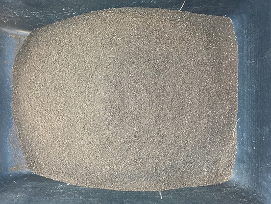 A black bin full of a brown soil-like substance.