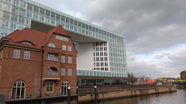 An old brick building in front of a larger modern office block.